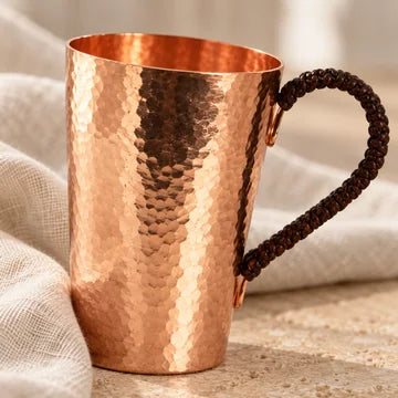 A hammered copper mug on stone and linen