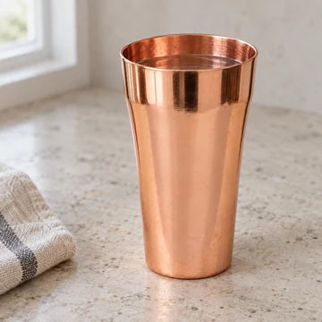 A polished copper cup on a pale stone surface